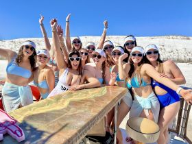 A lively group of friends celebrates a bachelorette party on a boat, enjoying the sun and beach vibes — perfect for unforgettable moments on the water.
