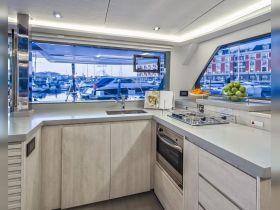 A modern boat kitchen featuring sleek cabinetry and a view of the marina, perfect for preparing meals while enjoying the scenic surroundings.