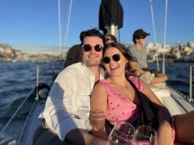 A joyful couple enjoys a sailing trip, clinking glasses and soaking up the sun — perfect for romantic getaways or celebrations on the water.