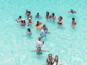 A lively group enjoys a refreshing swim in crystal-clear waters, perfect for beach fun and celebrations with friends and family.
