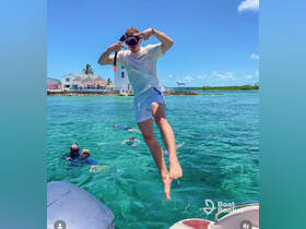 A young man jumps into the clear waters while others snorkel nearby, capturing the excitement of a fun-filled day on the water.