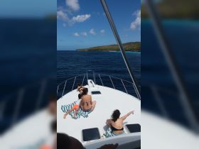 A group of friends relaxes on the bow of a boat, enjoying the stunning ocean views and nearby island scenery — perfect for family outings or group adventures on the water.