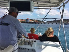 A group of people enjoying a scenic boat ride, with vibrant buildings and a bridge in the background, capturing the essence of a memorable cruise experience.
