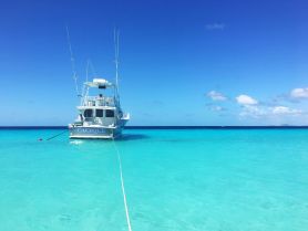 A stunning view of the 'Cacique' yacht anchored in crystal-clear turquoise waters, perfect for a day of relaxation and adventure on the sea.