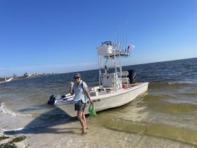 A person stands on the beach next to a fishing boat, showcasing a perfect day on the water. Ideal for fishing trips or beach adventures.