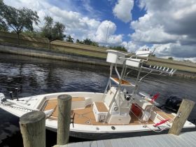 A sleek center console boat docked at the marina, showcasing its spacious deck and fishing features, perfect for a day on the water.