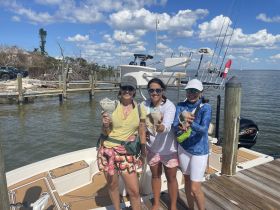 A group of friends proudly displays their shell finds while enjoying a day on the water, capturing the joy of a memorable boating adventure.