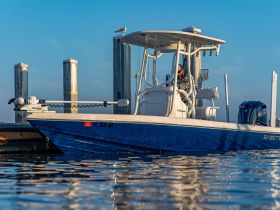 A sleek Skeeter boat docked at the marina, showcasing its design and features with a fisherman at the helm, perfect for fishing enthusiasts.