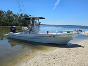 A sleek speedboat docked on a sandy shore, equipped for fishing with multiple rods ready for action. Perfect for a day out on the water.