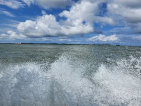 An unclear image capturing splashes of water with a distant view of the horizon and clouds, lacking identifiable subjects or clear focus.