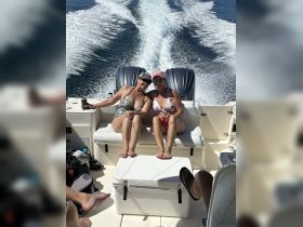 Two friends enjoy a sunny day on the boat, relaxing with drinks and laughter — a perfect moment for celebration on the water.