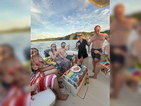 A lively group enjoys cocktails and snacks aboard a boat, celebrating together in a picturesque setting — perfect for summer gatherings and boat parties.