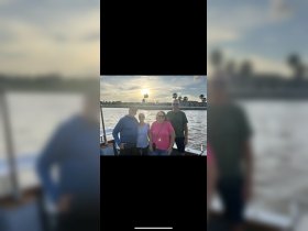A cheerful group poses for a photo on a boat at sunset, capturing a memorable moment during their water adventure.