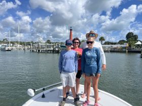A cheerful family poses on the bow of their boat at the marina, capturing a moment of togetherness before their adventure on the water.
