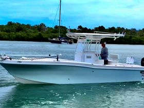 A man operates a boat in calm waters, showcasing the beauty of a day on the water — perfect for fishing or leisure activities.