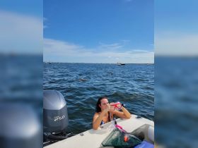 A woman prepares her snorkeling gear while enjoying a sunny day on the water, with others swimming nearby — a perfect scene for aquatic adventures.
