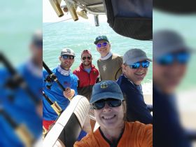 A cheerful group of friends poses for a selfie aboard a fishing boat, capturing the excitement of their day on the water.