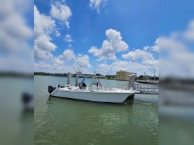 A fishing speedboat is docked at the marina, showcasing its sleek design and fishing gear, perfect for a day on the water.