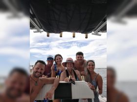 A cheerful group of friends enjoys drinks on a boat, capturing the essence of a fun-filled day on the water.