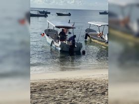 Two individuals prepare a boat in shallow waters, showcasing the vibrant boating culture and activities available on the coast.