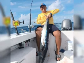 A proud angler displays a large catch while fishing on a boat, showcasing the thrill of deep-sea fishing adventures.