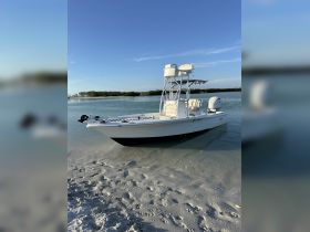A sleek boat anchored on a sandy shore, surrounded by calm waters and clear blue skies, perfect for fishing or leisurely outings.