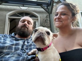 A candid moment featuring two adults and a dog, capturing a relaxed atmosphere. The image lacks clarity regarding the context.