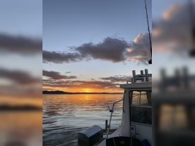 A serene sunset view from the deck of a boat, showcasing calm waters and a picturesque horizon — perfect for evening cruises.