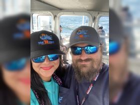 A cheerful couple poses for a selfie on a fishing boat, showcasing their excitement for a day on the water. Perfect for fishing enthusiasts and adventure seekers.