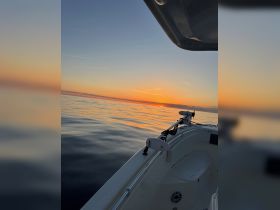 A serene sunset view from the deck of a boat, showcasing calm waters and a beautiful horizon — perfect for evening cruises.
