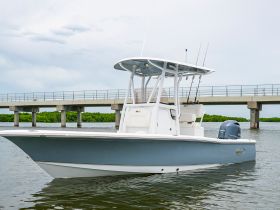 A sleek center console boat docked in calm waters, showcasing its modern design and fishing gear — perfect for a day on the water.