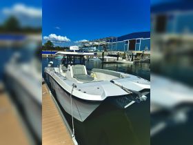 A sleek center console boat docked at the marina, showcasing its modern design and features against a clear blue sky.