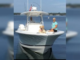 A couple enjoys a day on the water with their dog aboard a sleek boat, showcasing the perfect blend of relaxation and companionship on the open sea.