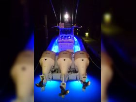 A striking view of a speedboat illuminated by blue lights at night, showcasing its powerful engines and sleek design — perfect for nighttime adventures on the water.