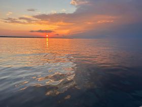 A breathtaking sunset over calm waters, reflecting vibrant colors — a perfect moment for relaxation and appreciation of nature's beauty.