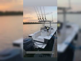 A sleek fishing boat equipped with multiple fishing rods, docked at sunset, perfect for a day on the water.