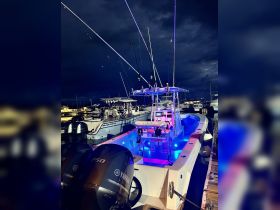 A striking view of a fishing boat illuminated with blue lights, docked and ready for an evening adventure. The sleek design and powerful Yamaha engines highlight its performance capabilities.