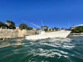 A boat is anchored near the shore while swimmers enjoy the clear waters, showcasing a perfect day for water activities.