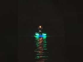 A striking view of a boat illuminated with colorful lights as it glides through the water at night, creating a captivating scene perfect for evening cruises.