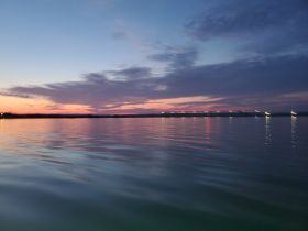 A serene sunset view over calm waters, showcasing beautiful reflections and a tranquil atmosphere — perfect for evening boat cruises.