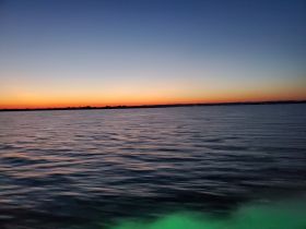 A serene sunset over calm waters, showcasing the tranquil beauty of evening boat rides.