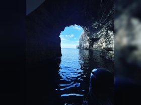 A stunning view from inside a cave, showcasing tranquil waters and a beautiful blue sky — perfect for exploring coastal wonders.