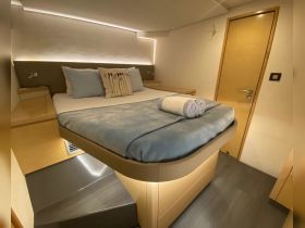 A cozy cabin interior featuring a comfortable bed with decorative pillows and soft lighting, perfect for relaxing on a boat getaway.