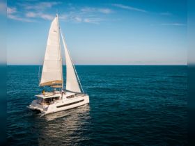 A stunning aerial view of a sleek catamaran sailing through clear blue waters, perfect for luxury charters and island adventures.