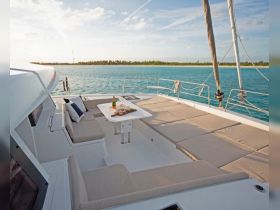 A beautifully arranged dining area on a yacht featuring comfortable seating, a bottle of champagne, and a platter of food, perfect for a luxurious day on the water.