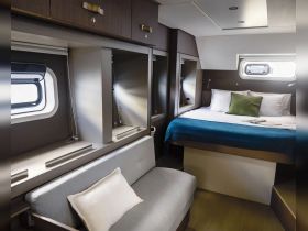 A cozy cabin interior featuring a comfortable bed and seating area, perfect for relaxing on a boat getaway.