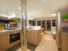 A modern and spacious interior view of a boat's kitchen area, showcasing sleek cabinetry and ample seating, perfect for onboard dining and entertaining.