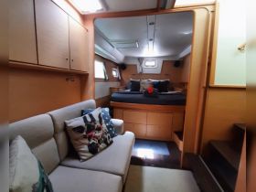 Interior view of a cozy boat cabin featuring comfortable seating and a well-appointed sleeping area, perfect for relaxing during a sailing trip.