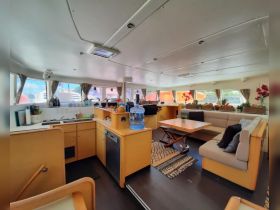 Interior view of a spacious boat cabin featuring a well-equipped kitchen and comfortable seating area, perfect for relaxing during your nautical adventures.