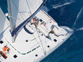 A couple enjoys a relaxing moment on the deck of a catamaran while sailing through vibrant blue waters, showcasing the perfect blend of adventure and romance.